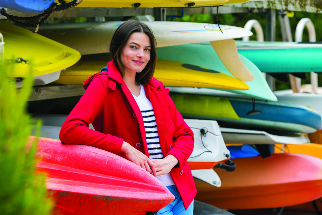 Nouvelle collection de vêtement Bastingage représenté par une femme souriante qui s'appuie sur des kayak